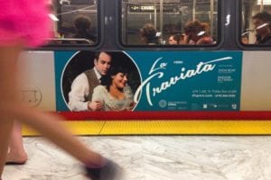 La Traviata advertisement on a train. A man embraces a woman in a circle.