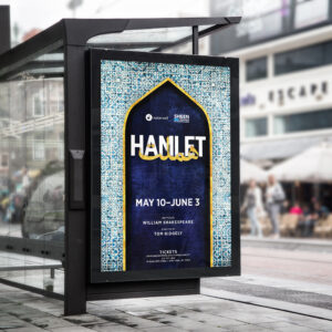 A poster at a bus stop advertises a production of Hamlet. The design, crafted by Denver Design Studio, features an arch with a mosaic pattern and text that reads: "HAMLET" and "May 10 - June 3." Below, it highlights the involvement of William Shakespeare and Tom Ridgley.