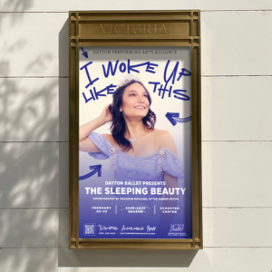 A theater poster for Dayton Ballet's "The Sleeping Beauty" shows a woman in a blue costume and tiara smiling, with handwritten text "I woke up like this" above her head.